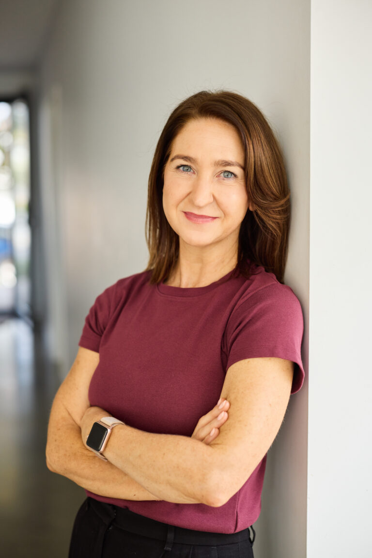Cate Carroll standing against a wall with her arms crossed