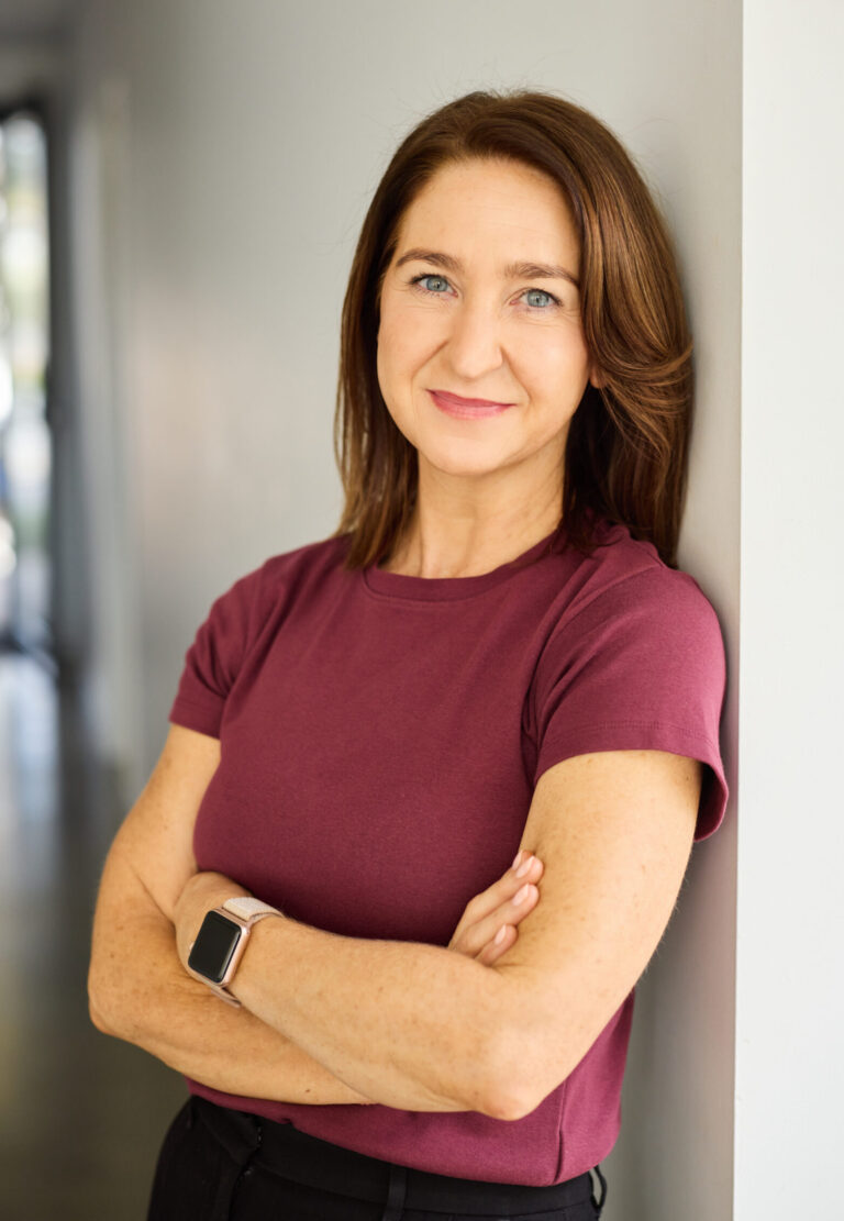 Cate Carroll standing against a wall with her arms crossed